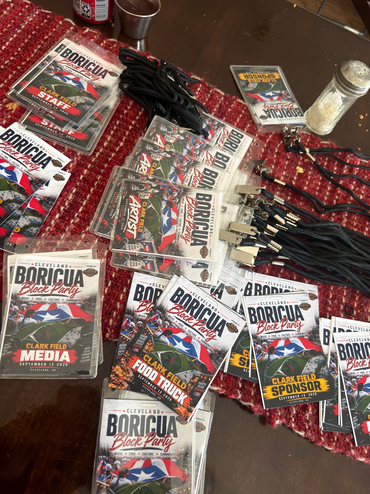 Block party staff, artist, media, food truck, and sponsor badges arranged with black lanyards on a table.