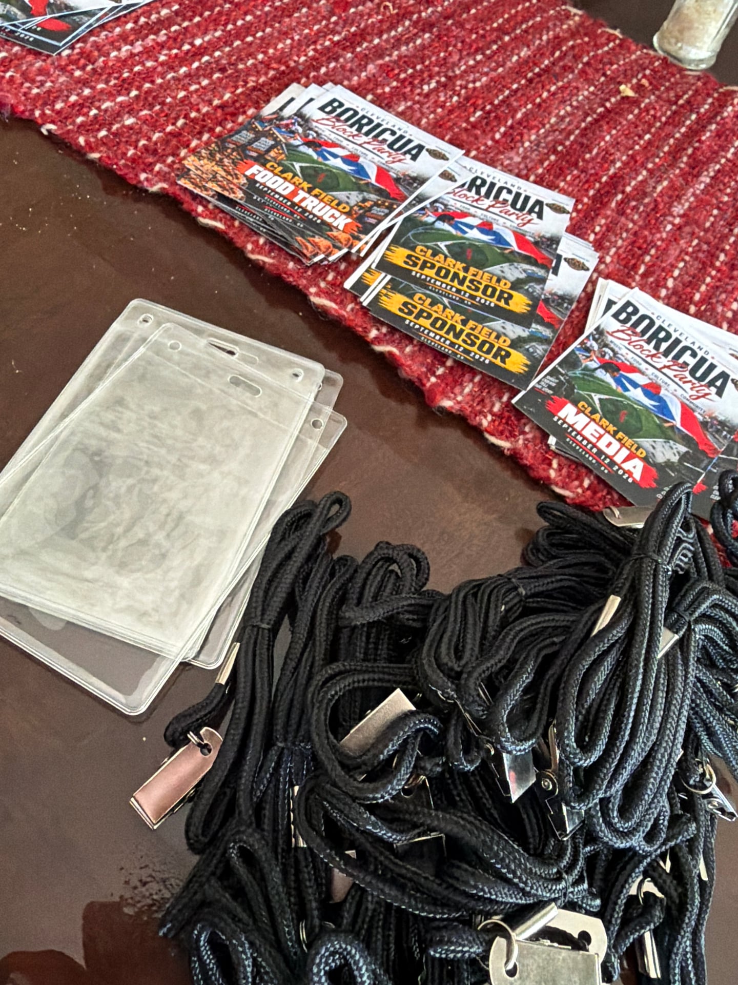 Printed block party badges, clear badge holders, and black lanyards laid out on a tabletop.