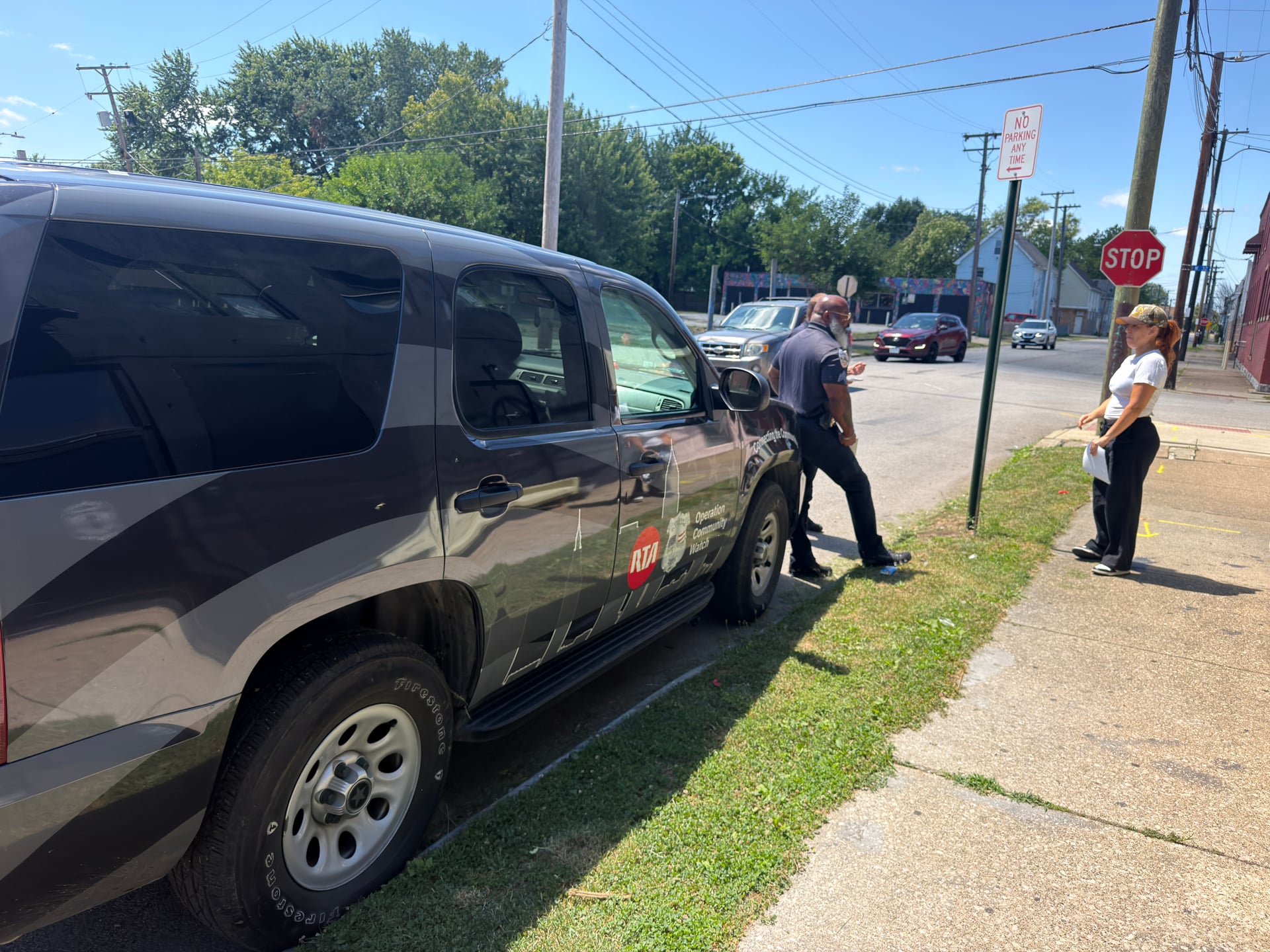 People talking on a sidewalk beside an RTA Operation Community Watch vehicle.