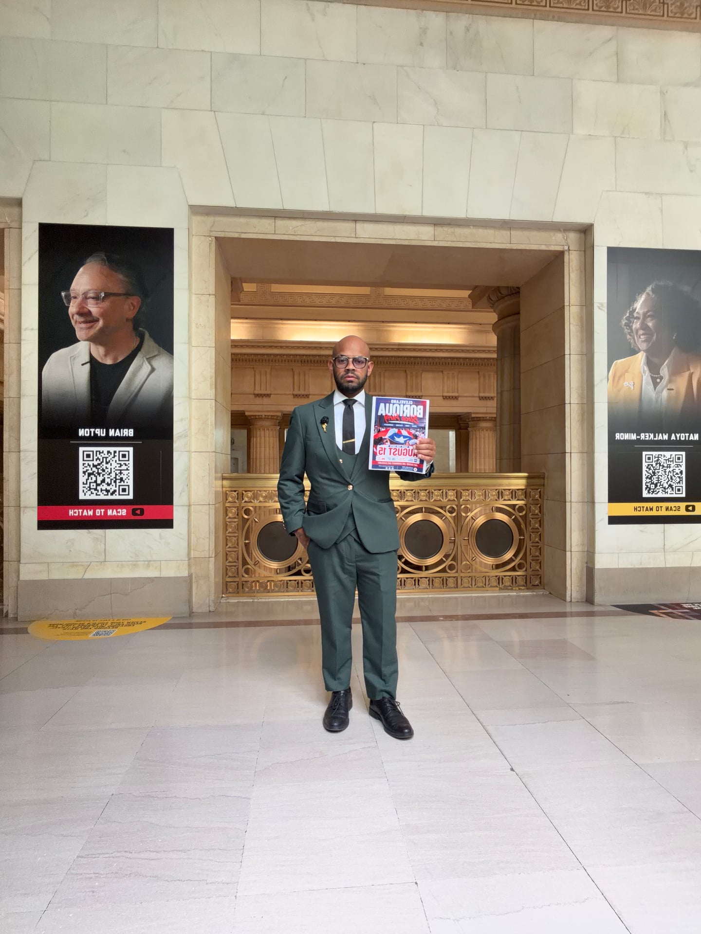 A person in a green suit holding an early block party flyer in a large stone hall.