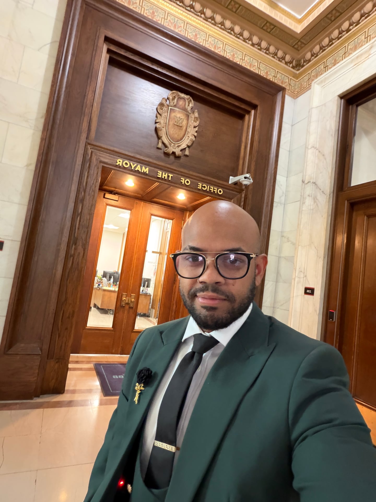 A selfie in a stone hallway outside a doorway labeled Office of the Mayor.