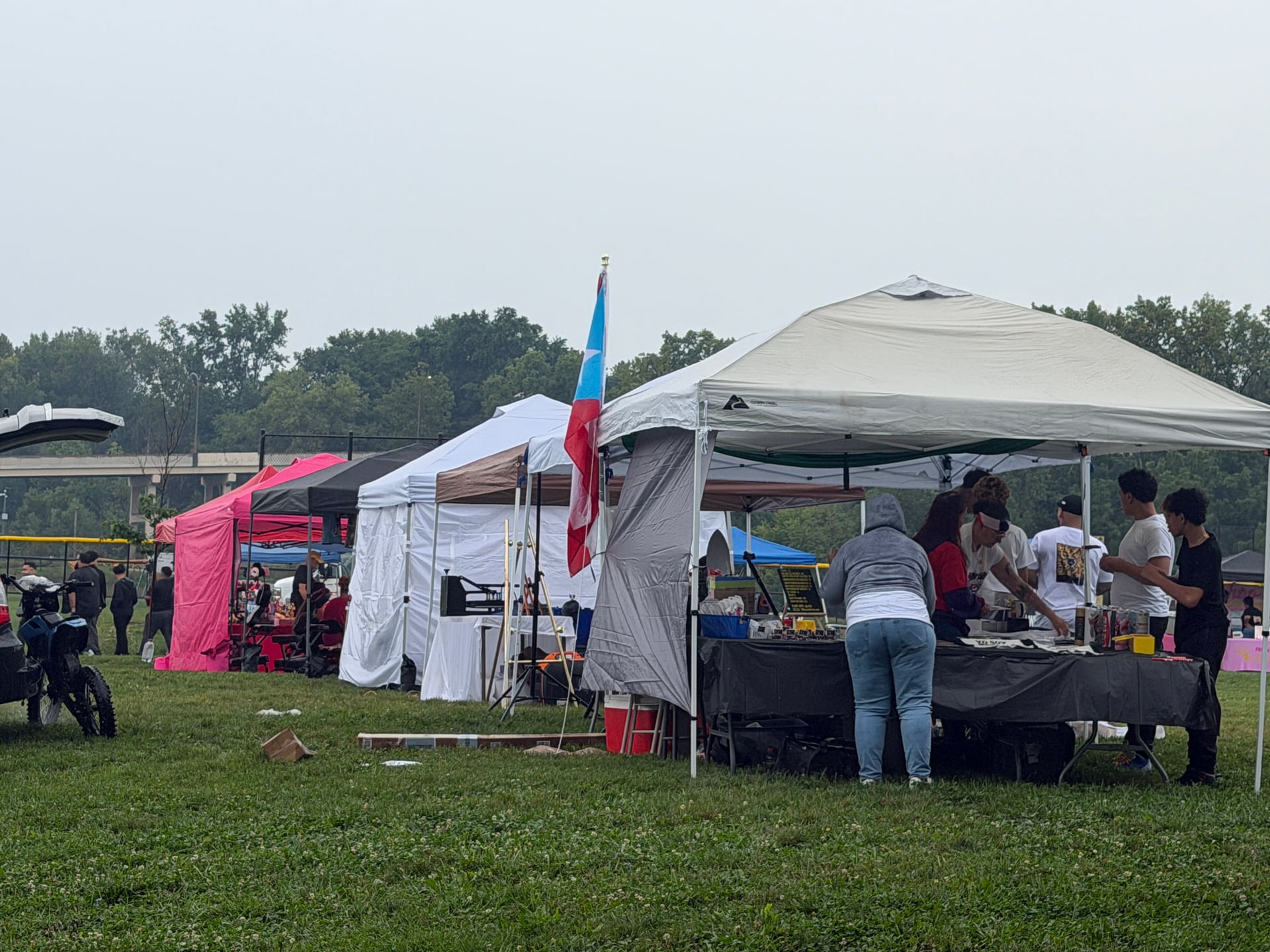 A row of colorful vendor canopies with visitors gathered around tables.