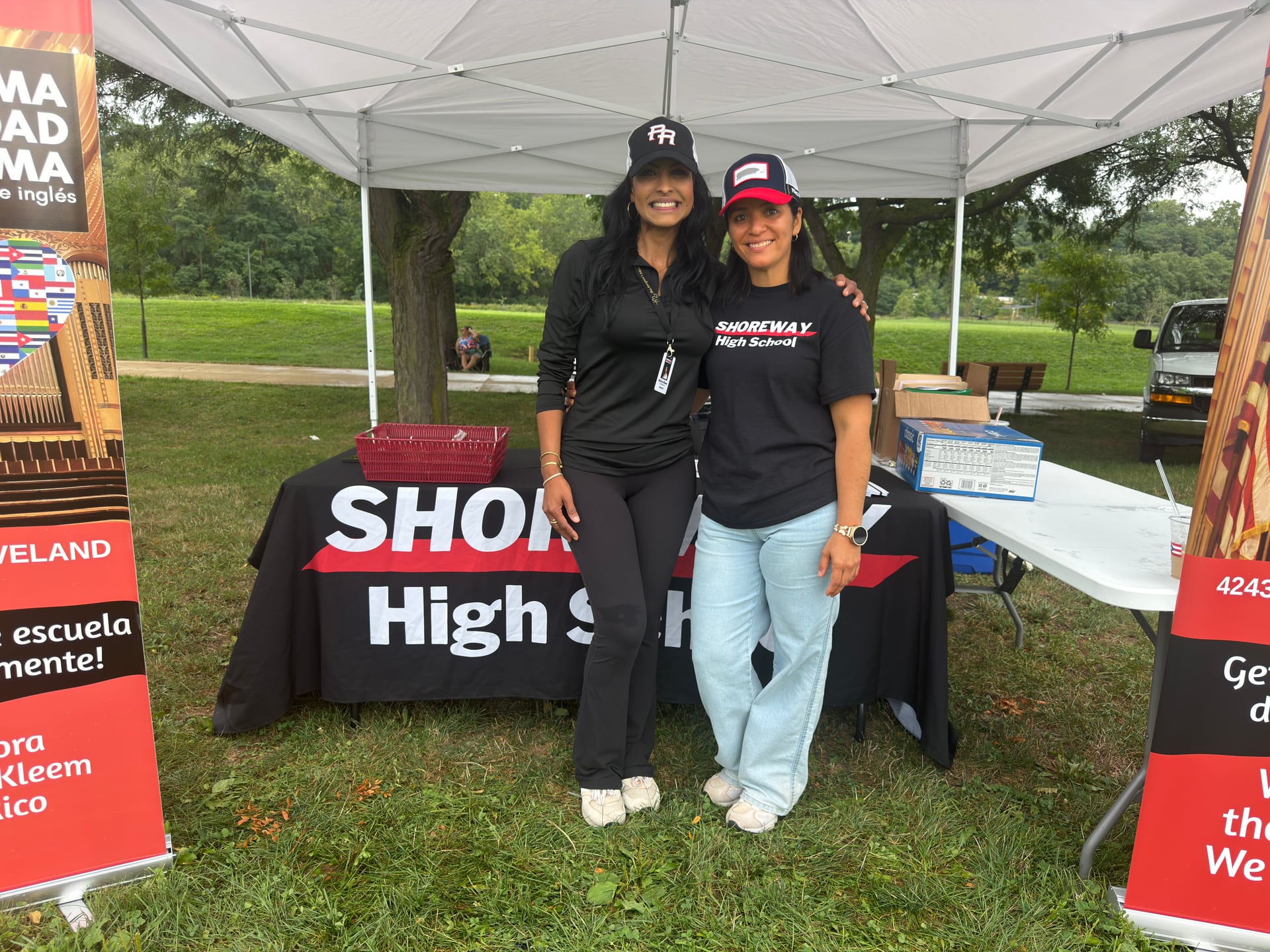 Two people posing in front of a Shoreway High School table beneath a white canopy.