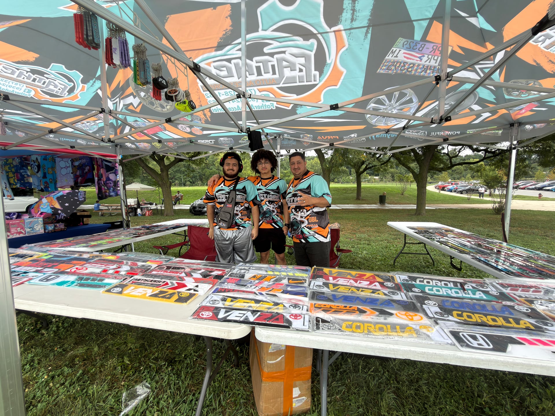 Three people in matching shirts posing behind a display of automotive accessories.
