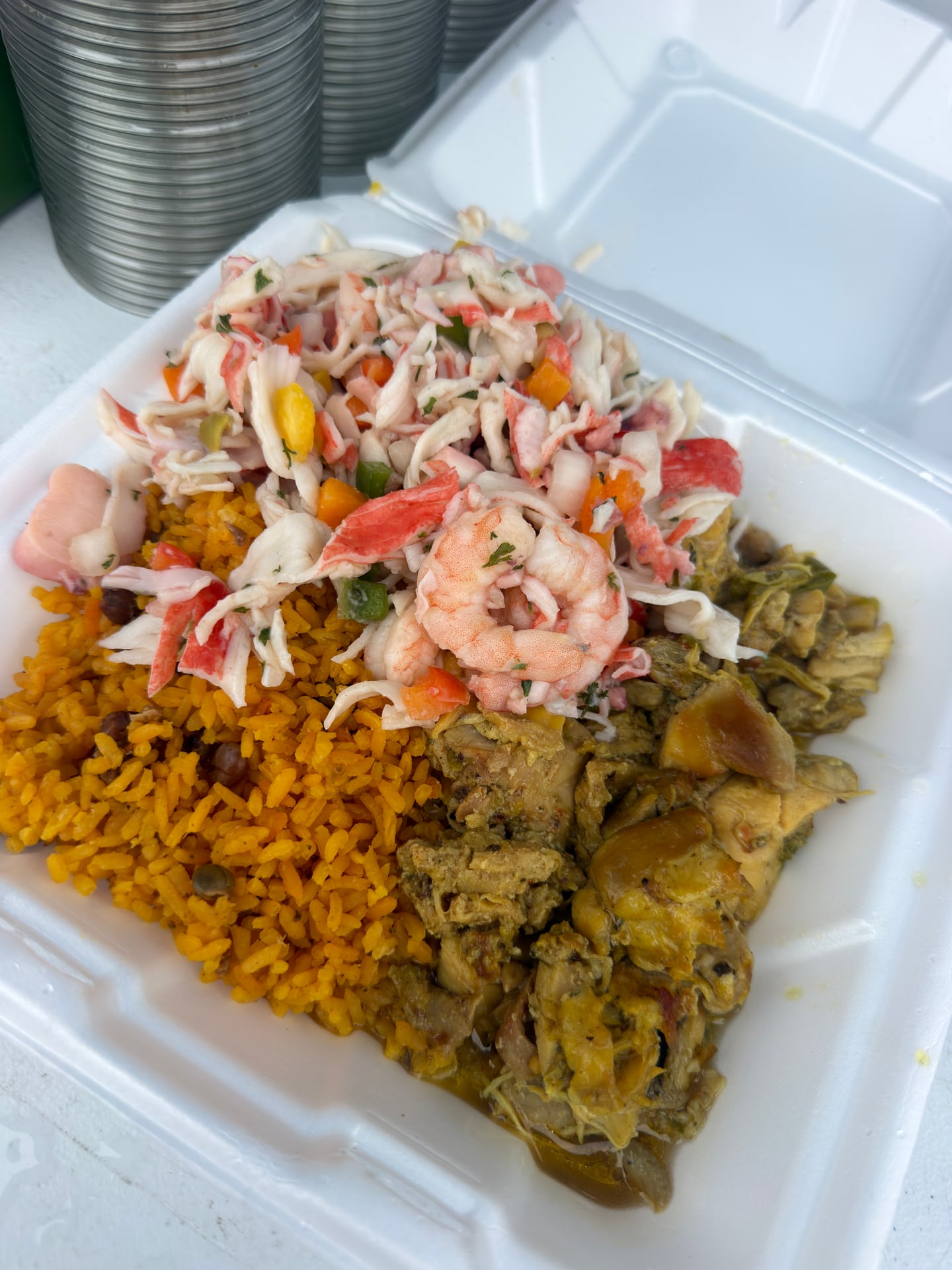 Close-up of an open takeout container with rice, shrimp, and other prepared food.